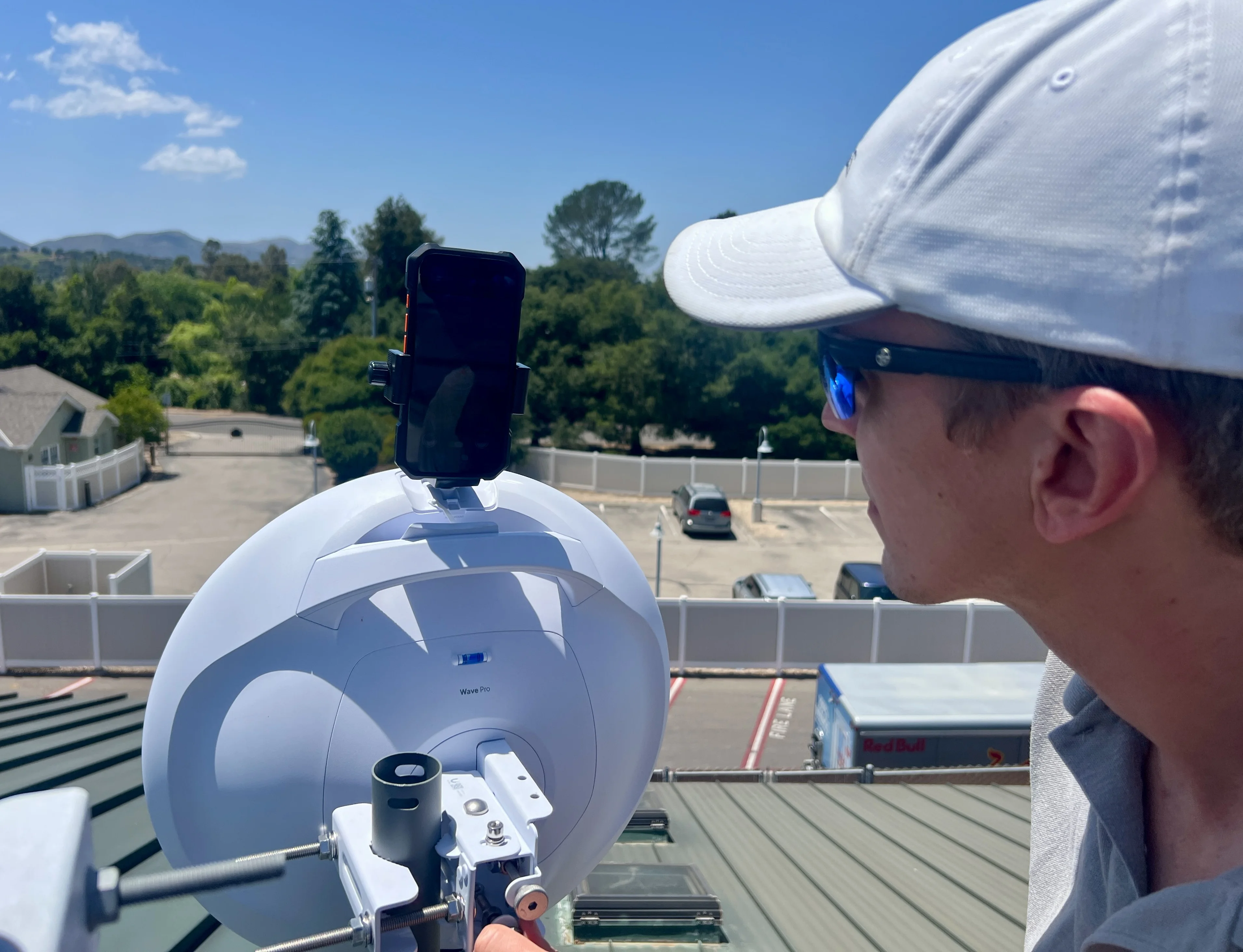 Technician aligning a Ubiquiti Wave Pro with iPhone mounted on the built-in ¼-20 tripod boss
