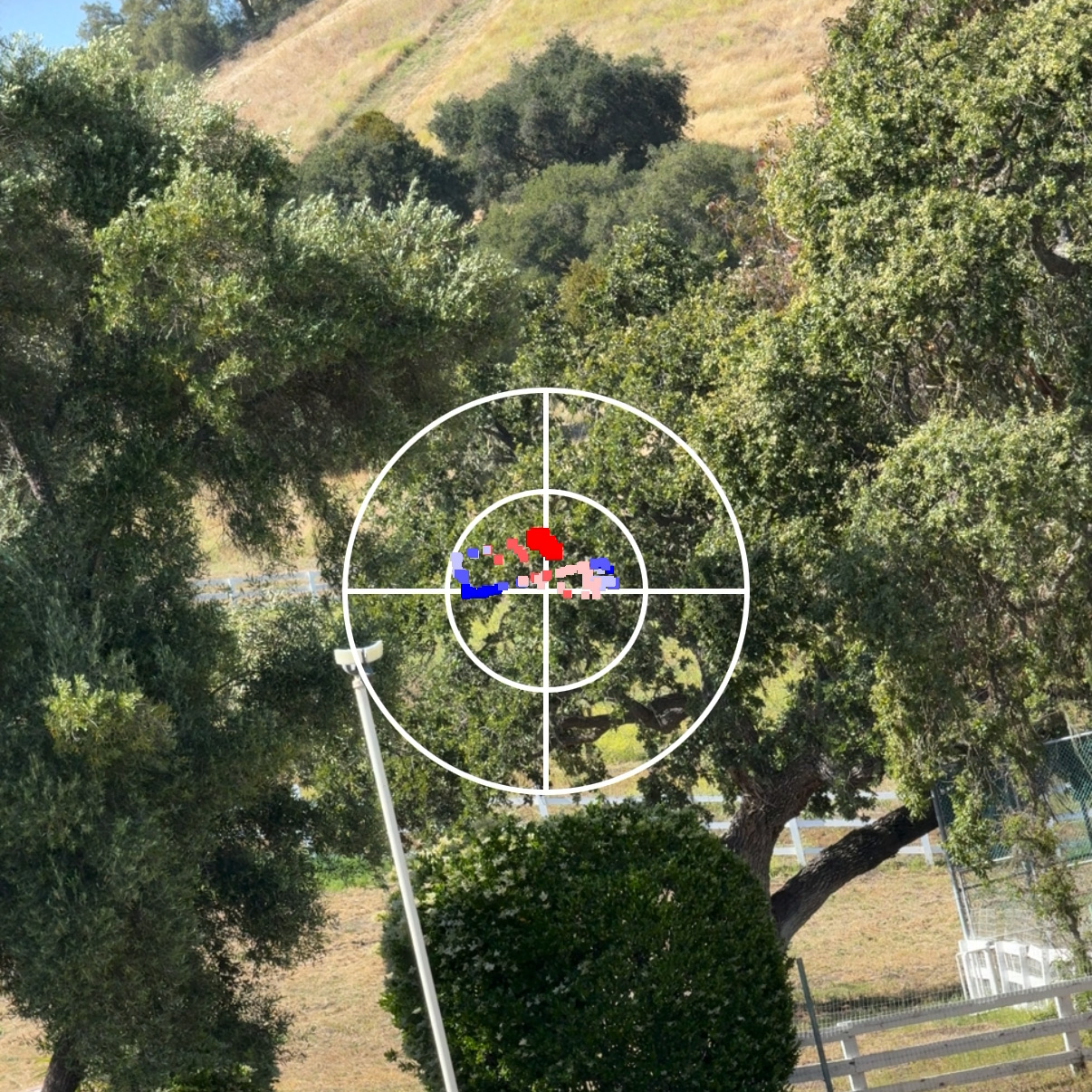 Phone mounted on CPE antenna mast with signal overlay visible through oak trees, demonstrating the camera does not need to point exactly at the far end
